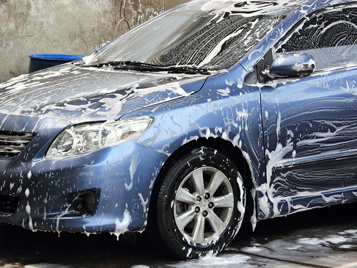 washing a blue car with a foam and water